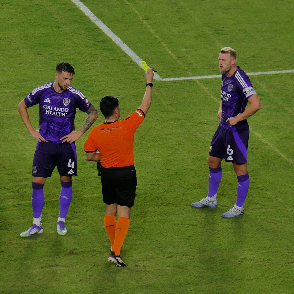 Árbitro mostrando la tarjeta amarilla a un jugador